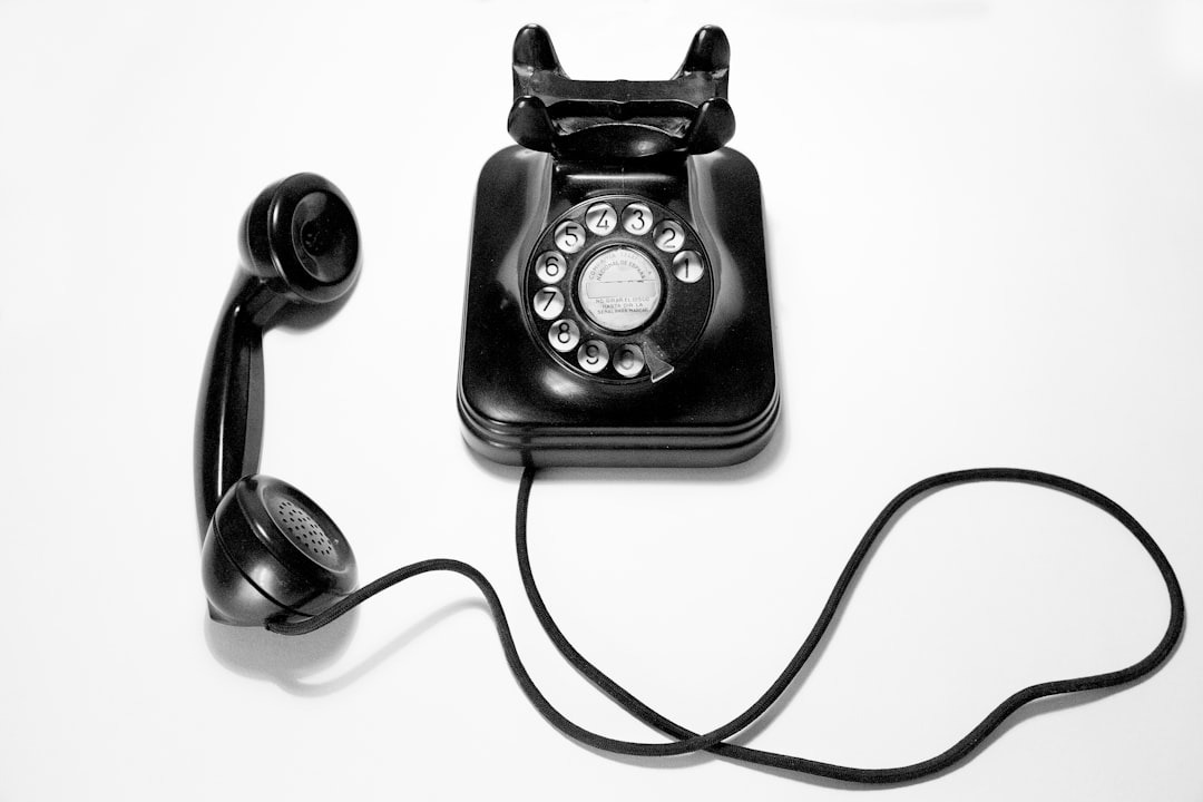 Vintage black rotary telephone with receiver off the hook.